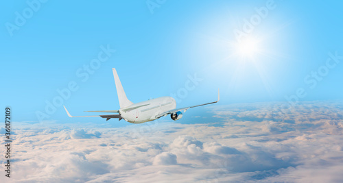 White passenger airplane in the clouds with sunrays - Travel by air transport