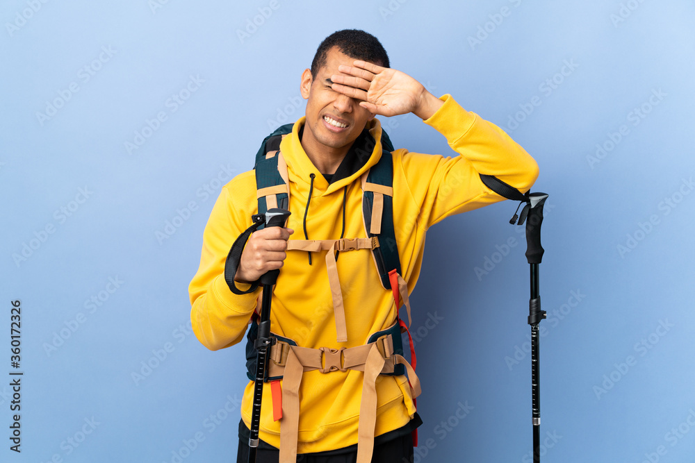 African American man with backpack and trekking poles over isolated background with tired and sick expression African American man with backpack and trekking poles over isolated background with tired and sick expression