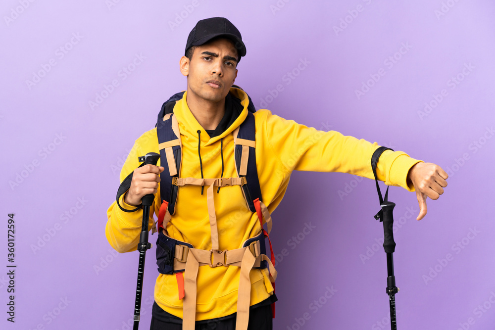 African American man with backpack and trekking poles over isolated background showing thumb down with negative expression African American man with backpack and trekking poles over isolated background showing thumb down with negative expression