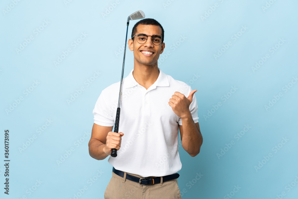 Fototapeta premium African American man over isolated blue background playing golf and with thumbs up because something good has happened