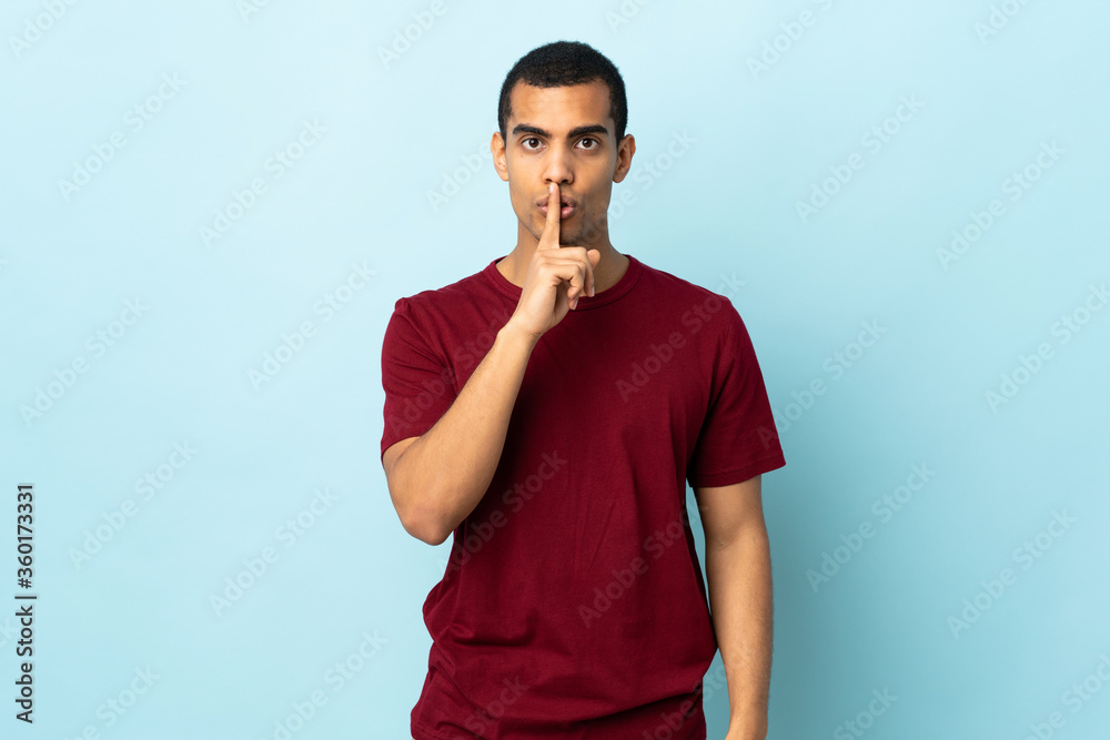 African American man over isolated background showing a sign of silence gesture putting finger in mouth African American man over isolated background showing a sign of silence gesture putting finger in mouth