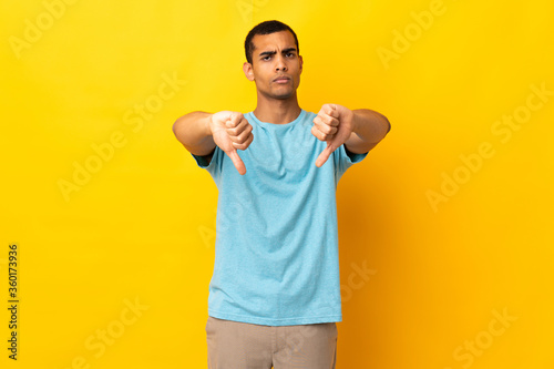 African American man over isolated background showing thumb down with two hands