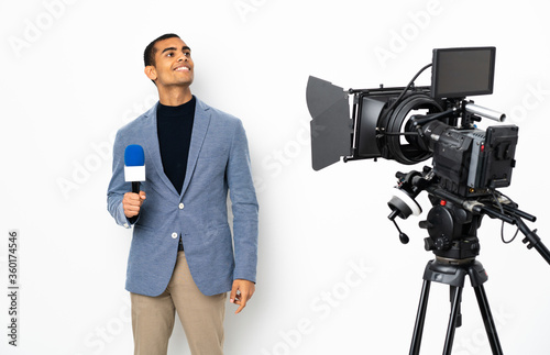 Reporter African American man holding a microphone and reporting news over isolated white background thinking an idea while looking up