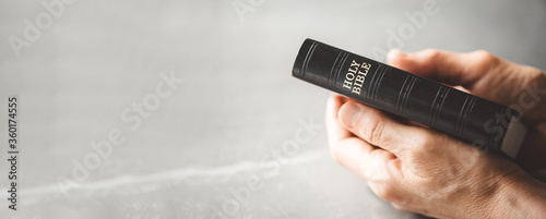 Photography Hands holding Holy Bible over grey background