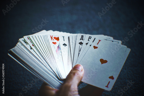 Human hand holding a fan of playing cards on a dark blue background.
