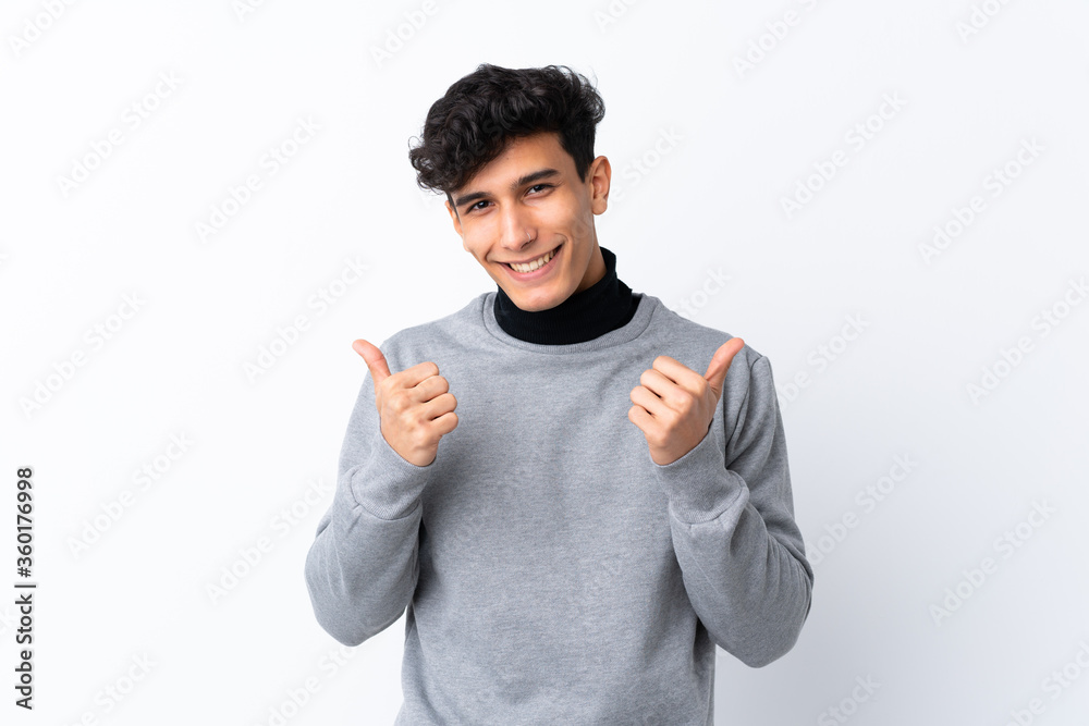 Young Argentinian man over isolated white background with thumbs up gesture and smiling