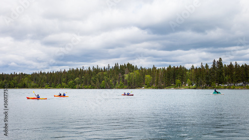 People on kayaks and paddle boats in Clear Lake in Wasagaming, Manitoba on a cloudy day