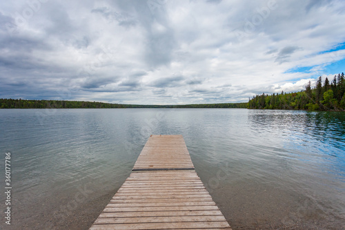 Wooden dock extending out to Clear Lake in Wasagaming, Manitoba on a cloudy day photo