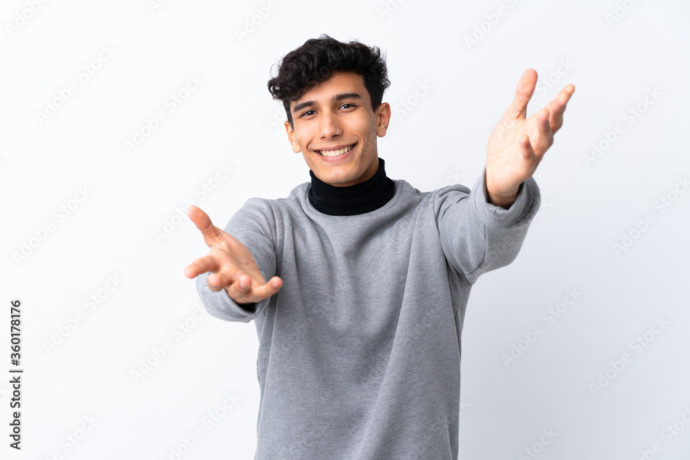 Young Argentinian man over isolated white background presenting and inviting to come with hand Young Argentinian man over isolated white background presenting and inviting to come with hand