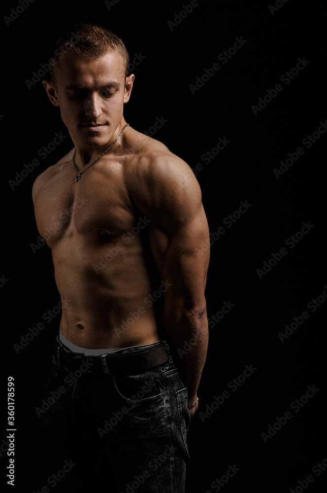 View of a muscled man on a black background in artistic, fitness and bodybuilding poses.