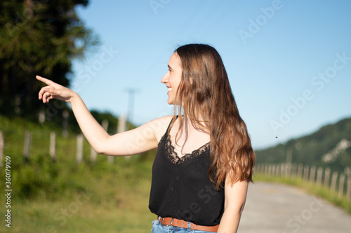 girl pointing something with her arm up on a sunny day
