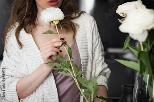 Young attractine woman makes a bouquet of white peonies in a vase photo