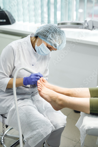 Side view female podologist making medical pedicure in beauty salon