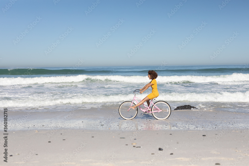 Fototapeta premium Mixed race woman riding bike on the beach