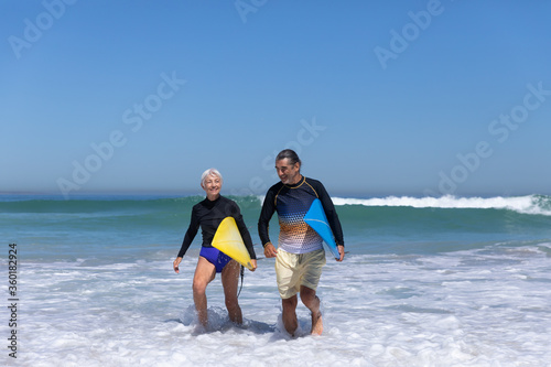 Senior Caucasian couple holding surfboards at the beach.