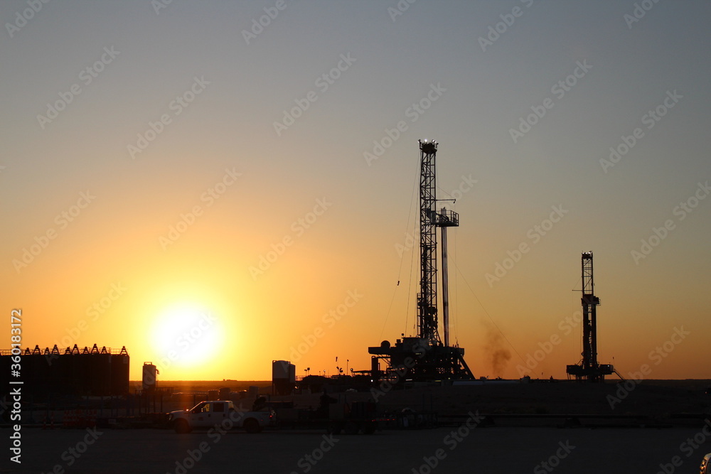 sunrise with 2 drilling rigs in the background