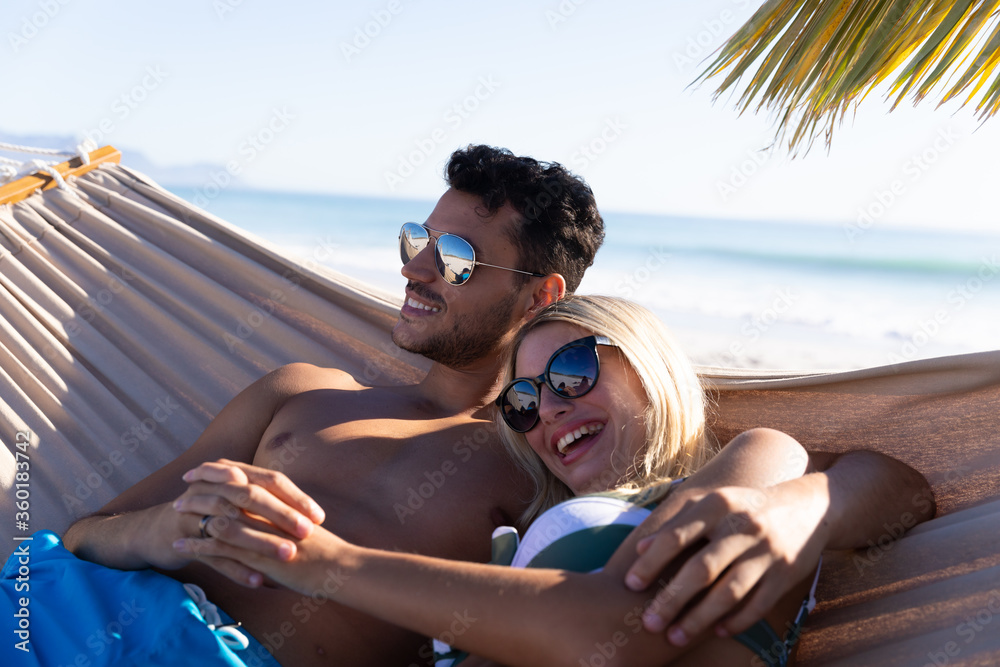 Fototapeta premium Caucasian couple lying on a hammock at the beach.