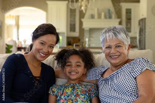 Mixed race woman sitting on the couch with her senior mother and her young daughter