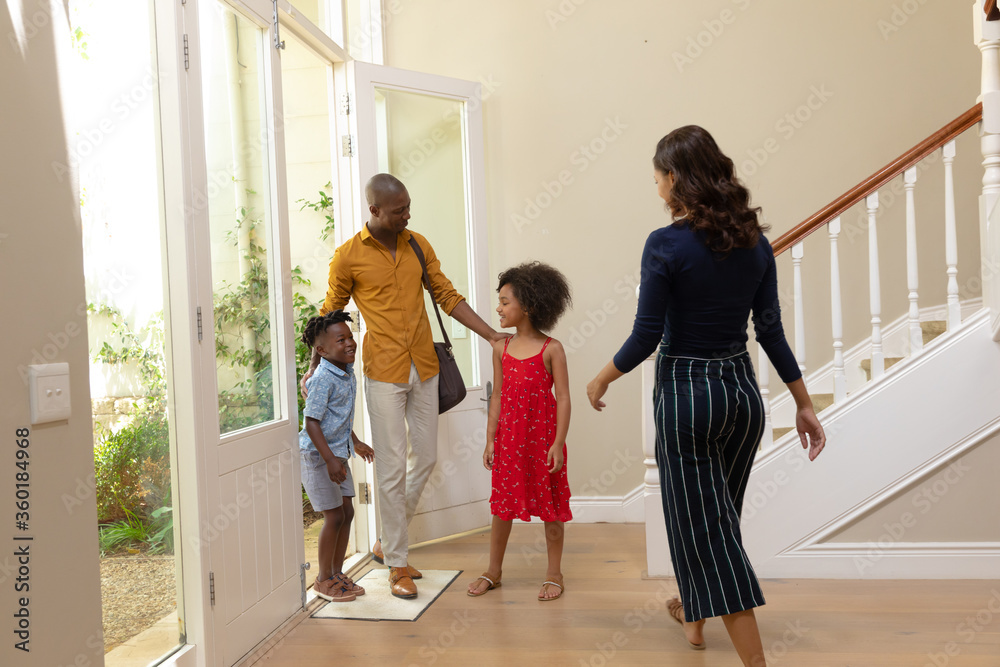 Mixed race couple and their young son and daughter standing in the hallway of their home