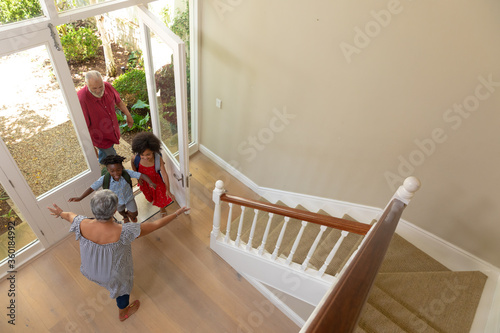 Mixed race senior man arriving home with his grandson and granddaughter