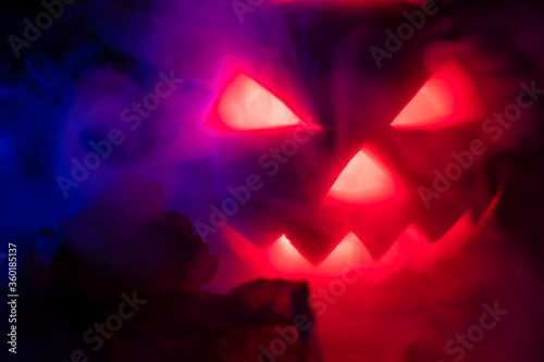 Glowing pumpkin in the dark releasing smoke from the eyes and mouth close-up. Background for Halloween.
