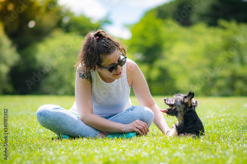 young woman with beautiful yorkshire posing and playing sympathetically in a garden with grass and trees. photo