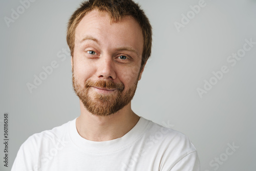 Photo of joyful young man with red hair posing and smiling on camera