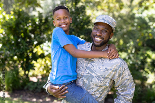 African American man wearing a military uniform holding his son