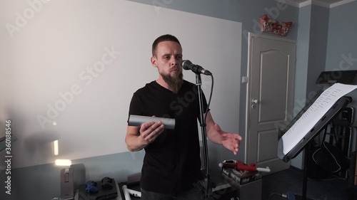 Young musician singing into microphone while recording new song at home