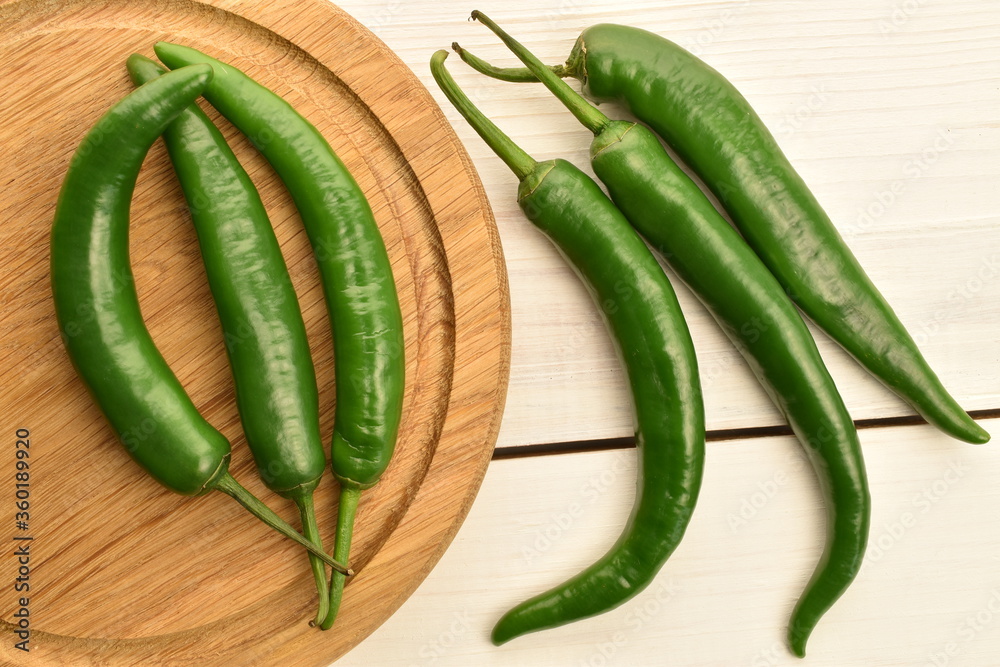 Green chili pepper, close-up, on a white wooden table. Green chili pepper, close-up, on a white wooden table.
