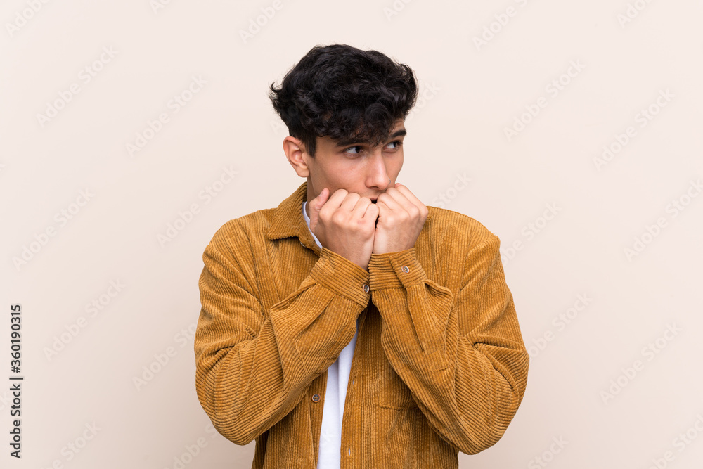 Young Argentinian man over isolated background nervous and scared putting hands to mouth Young Argentinian man over isolated background nervous and scared putting hands to mouth