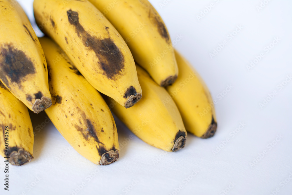 A bunch of Canarian bananas, yellow with black specks, isolated on white background.