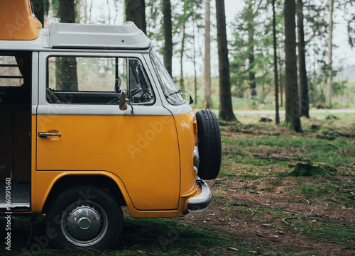 Orange retro Bulli Vintage Camper in green forest.