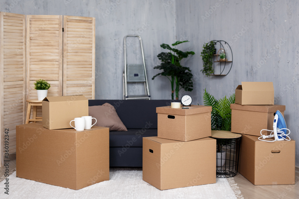 Fototapeta premium moving day concept - brown cardboard boxes with belongings stacked in new house