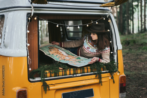 Traveler girl sitting in the retro car looking map.
