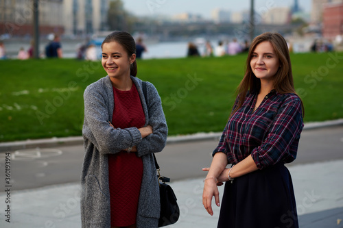 Two beautiful women tourists are standing on the street and thinking where to go on excursion during their weekend abroad. Cheerful hipster girls are resting after walking tour during spring vacation © BullRun