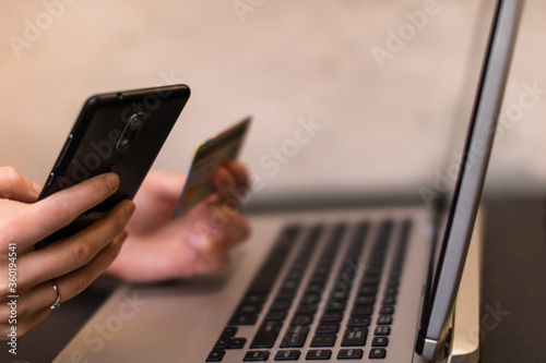 Hands holding credit card and using smartphone and laptop. Online shopping, on line payment concept