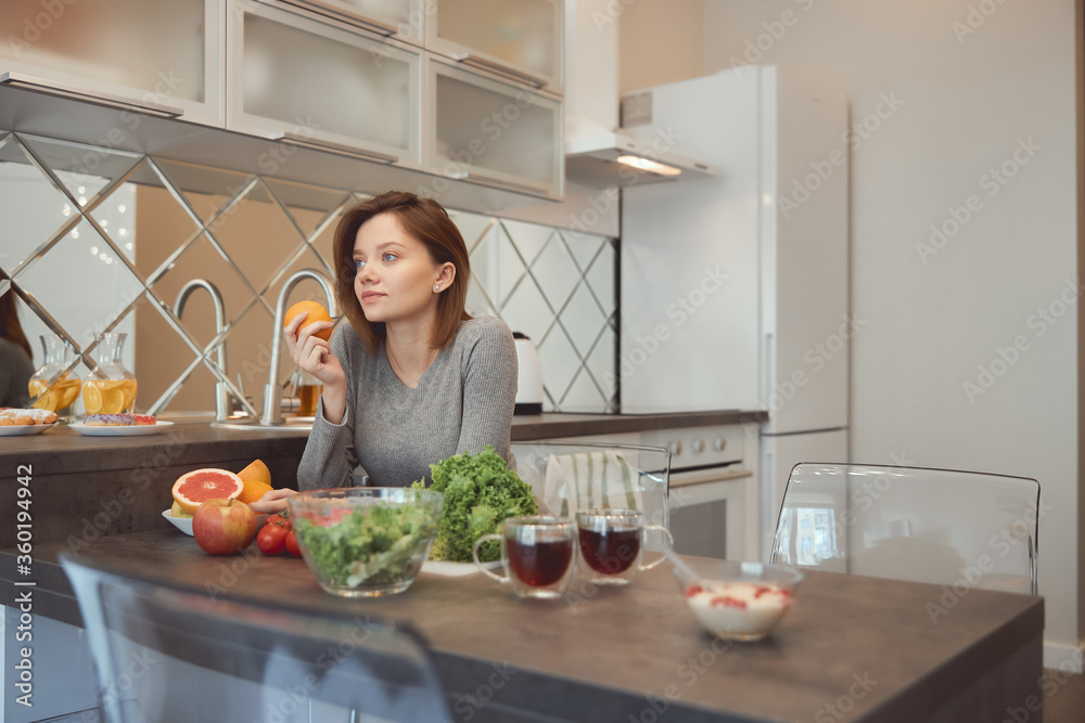 Calm young lady in the kitchen with tasty healthy food