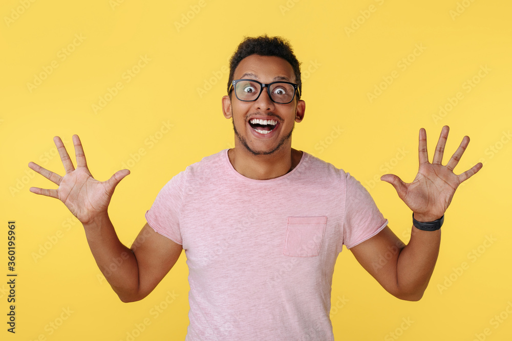 Amazed successful african american young man celebrate victory with hands wide open over yellow background. Amazed successful african american young man celebrate victory with hands wide open over yellow background.