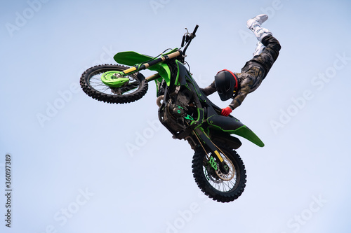 rider in protective uniform and helmet does a dangerous stunt in the air on a motorcycle. jump and flight on a motorcycle. extreme sport. motor freestyle