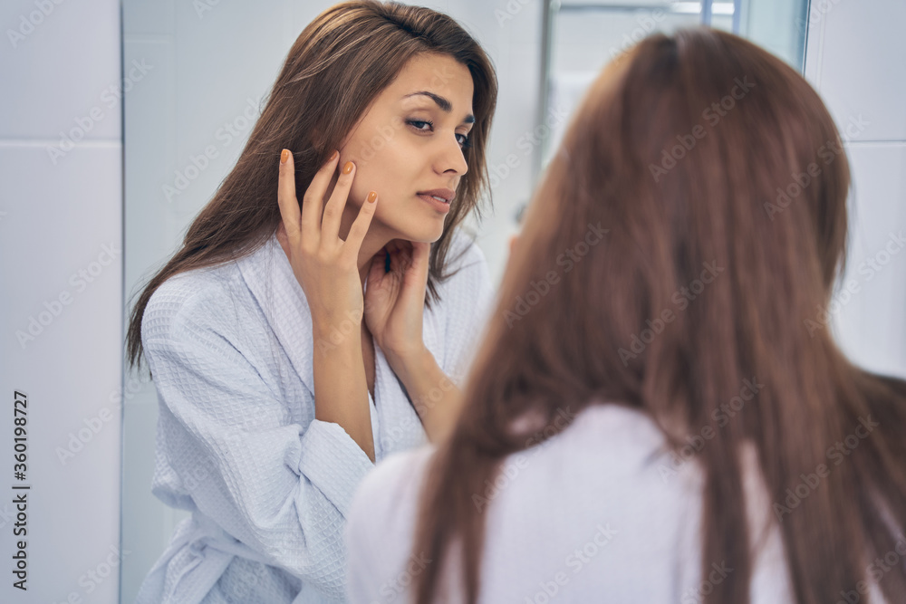 Beautiful lady looking in the mirror in bathroom Beautiful lady looking in the mirror in bathroom