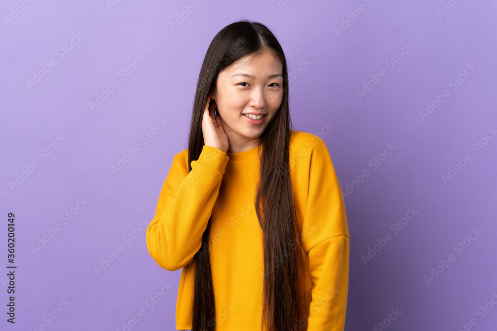 Young Chinese girl over isolated purple background laughing