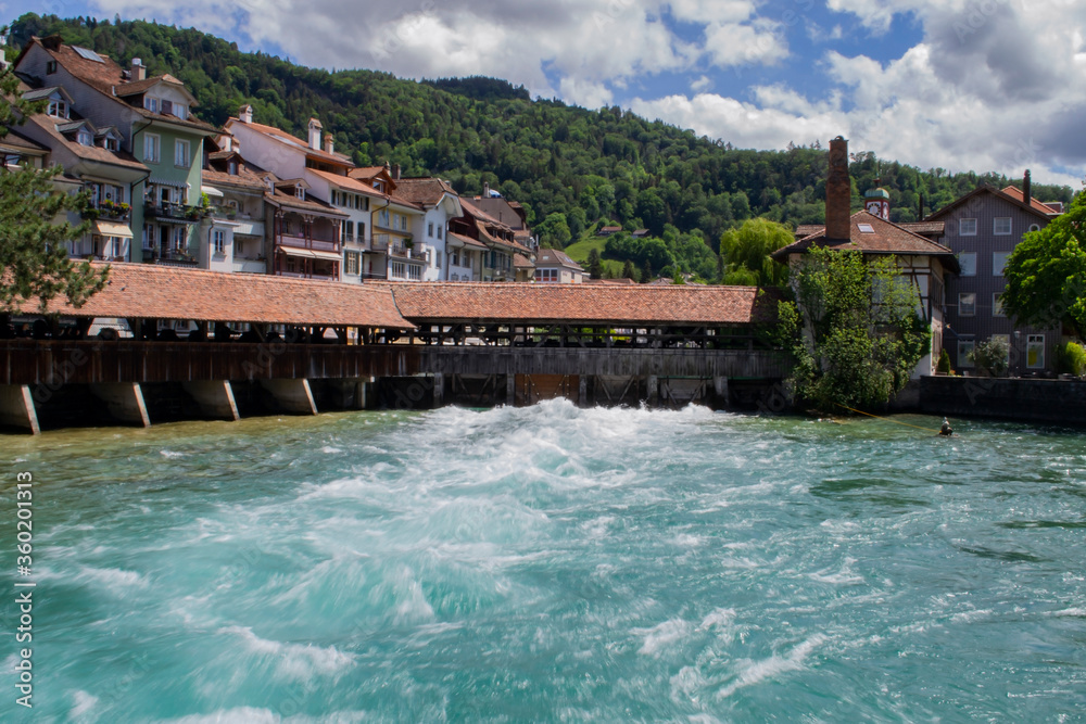 view of the turbulent river flow at the dam and beautiful houses near the coast in Switzerland in Thun