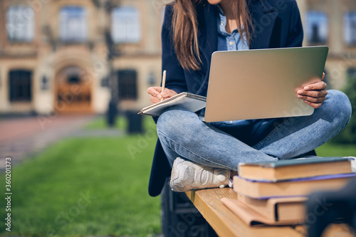Female in casual clothes spending time outdoors and studying photo