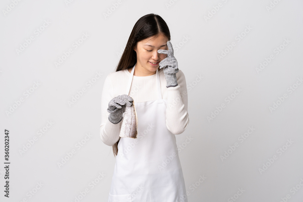 Chinese fishmonger wearing an apron and holding a raw fish over isolated white background laughing Chinese fishmonger wearing an apron and holding a raw fish over isolated white background laughing