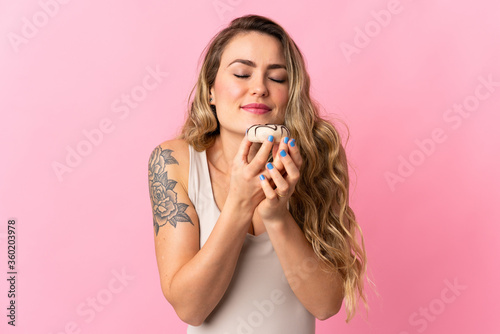 Young Brazilian woman isolated on pink background holding a donut