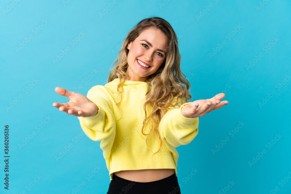 Young Brazilian woman isolated on blue background presenting and inviting to come with hand Young Brazilian woman isolated on blue background presenting and inviting to come with hand