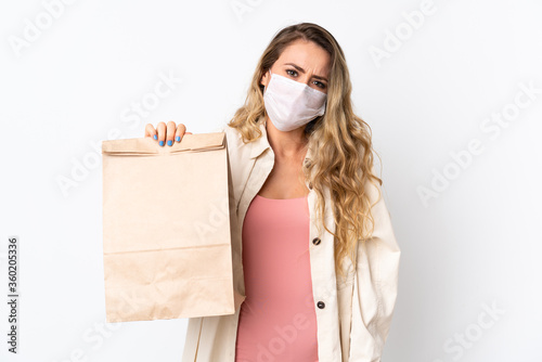 Young woman holding a grocery shopping bag isolated on white background with sad expression