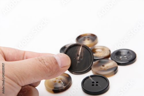 One hand picked one up from a pile of buttons.