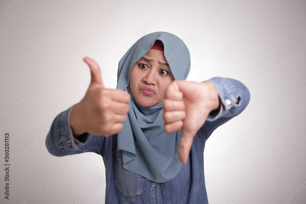 Naklejka premium Muslim woman shows thumbs up and down gesture